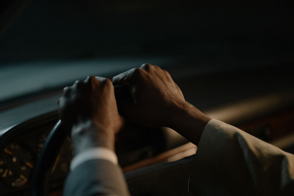 Close-up of a driver's hands on a steering wheel in low light