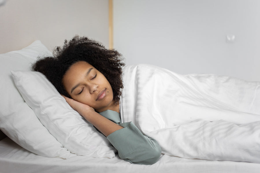 A woman sleeping peacefully on white bedding