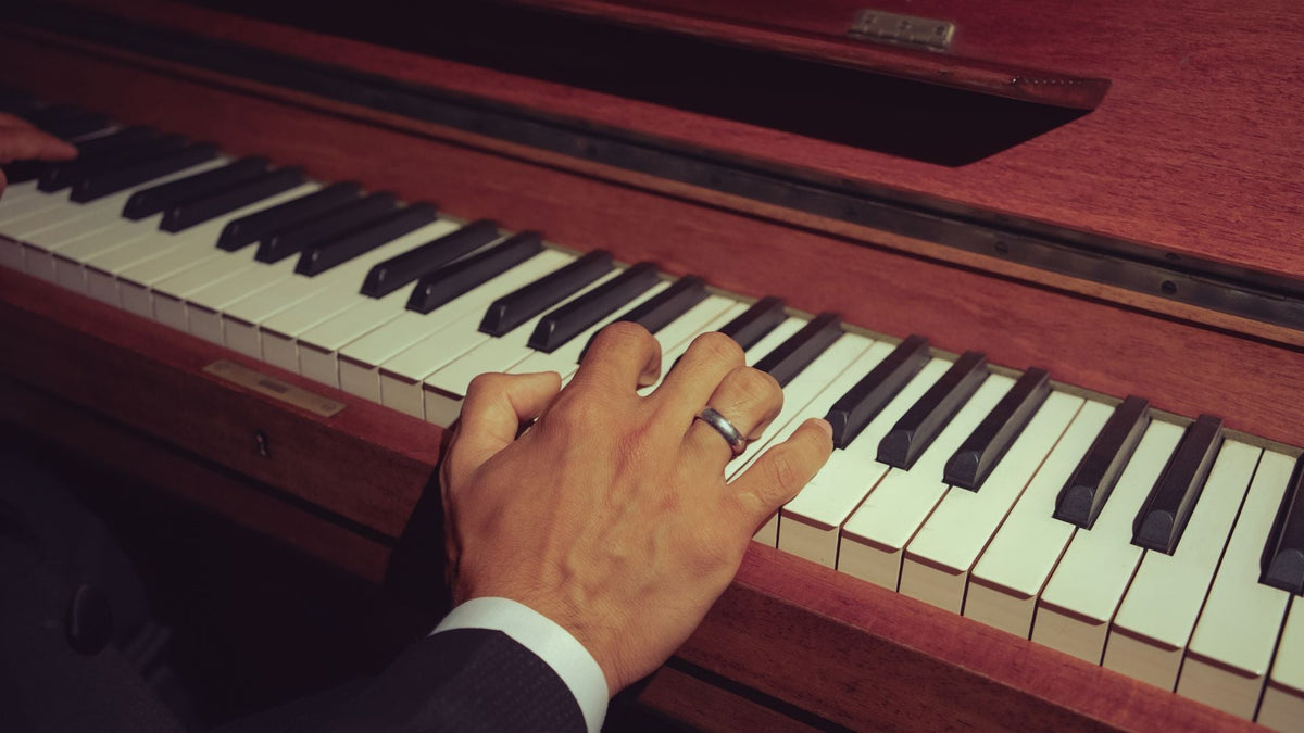 Hands playing an upright piano