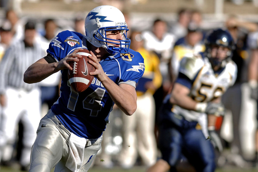 An American football quarterback in a blue jersey preparing to throw
